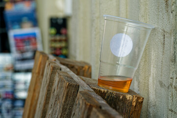 Disposable Plastic Cup with Yellow Liquid on Wooden Pallet by Wall in Copenhagen CPH