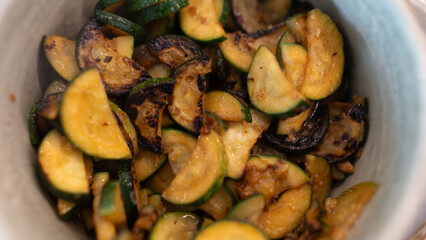 Golden fried zucchini with aromatic herbs served in a rustic bowl. Healthy vegetable dish perfect for food photography, vegan recipes, and clean eating content