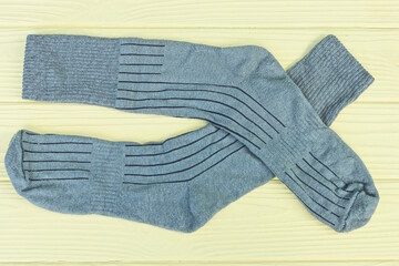 two gray long fabric socks lie on a yellow wooden table