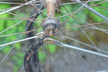part of an old bicycle made of gray metal spoked wheels on a blue frame on the street
