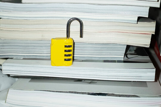 Yellow lock / padlock in bookshelf with hard direct flashlight
