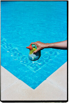 man trying to drown a penguin-shaped floaty, 35mm