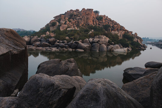 A pile of boulders in the middle of a lake. 