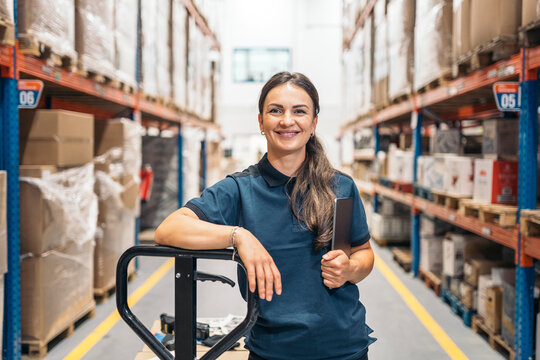 Smiling female logistic worker holding tablet and leaning