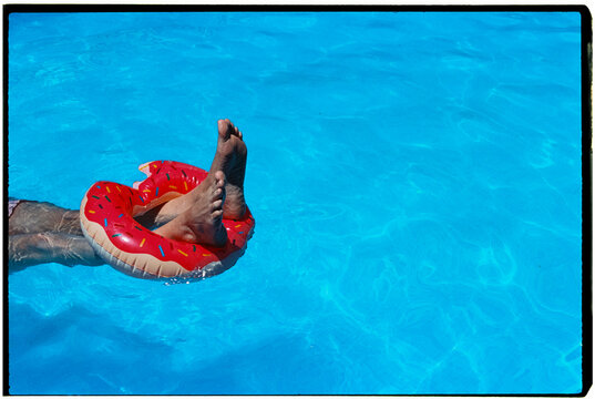 man floating with feet on a donut-shaped inflatable, 35mm