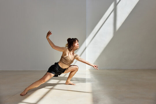Dancer performs dynamic movement in sunlight filled studio