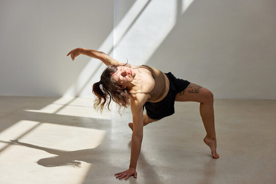 Dancer performs dynamic movement in sunlit studio space