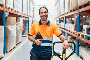 Warehouse worker smiling and holding tablet near pallet jack