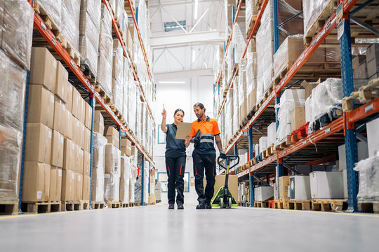 Warehouse workers checking inventory using clipboard and pallet jack