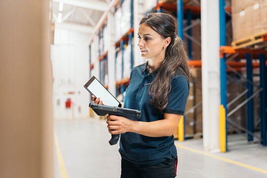 Worker scanning packages with barcode scanner, using tablet