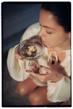 Woman drinking cocktail of wine and golden earring