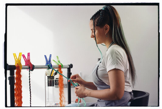 Beautician weaving hair extensions at beauty shop