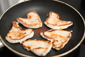 Grilled chicken breast fillets in nonstick pan on stovetop for healthy meal prep.