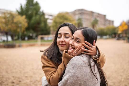 Teen sisters hugging cheek to cheek