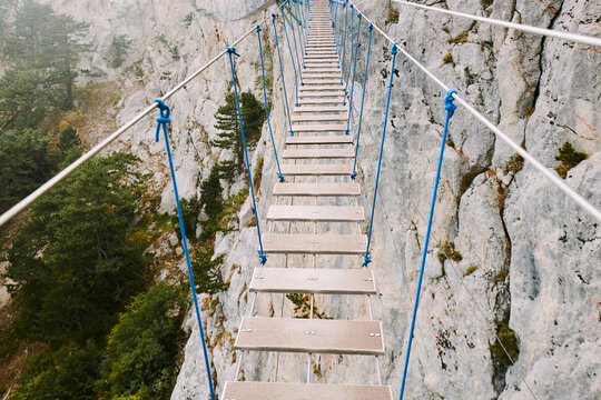 Suspended walkway among rugged cliffs in a misty landscape