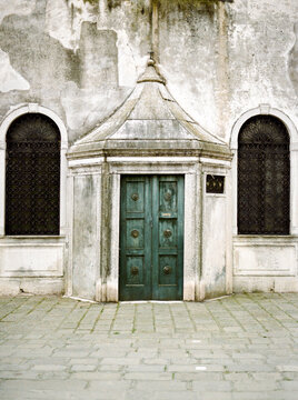 Detail of green wooden carved door and peeling church facade