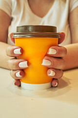 Woman holding a cup with a brown lid