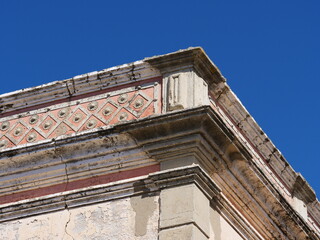 upper corner of a building with architectural details; the façade features a series of diamond-shaped decorations with floral patterns