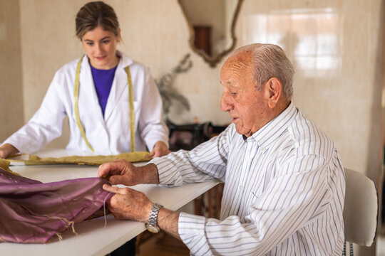 Senior man sewing under designer supervision