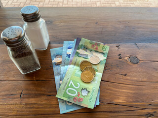 Canadian cash paper money payment on restaurant wooden table