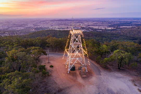 Sunet over a tall steel lookout tower strung with lights