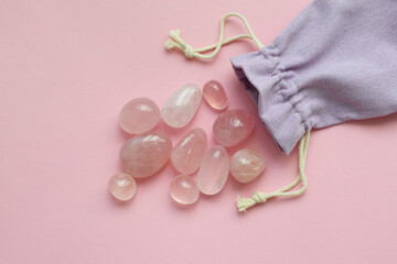 Beautiful natural semi-precious stones of rose quartz in a cloth bag on a pink background. Healing crystals, predictions and talismans.