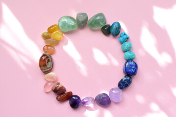 Precious stones for zodiac signs on a pink background in the sunbeams. The circle is laid out with natural minerals. Predictions, witchcraft, spiritual esoteric practice.