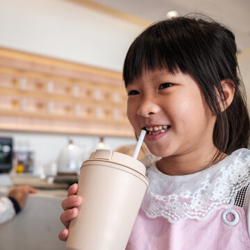 Young Girl Enjoying a Drink in a Cozy Cafe Setting