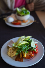 Breakfast plate features a fried egg, cooked tomato, lettuce, meat