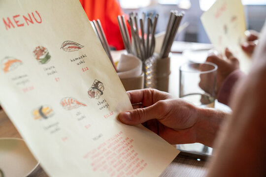 Close-up of sushi menu held by customer
