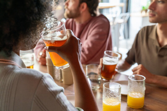 Woman in front holding beer glass at cafe