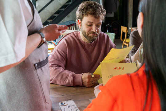 Man holding menu while ordering at cafe