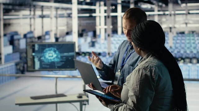 Server room coworkers use laptop to install updates and keep AI systems running. Data center engineering team uses notebook to write code improving infrastructure output, camera B