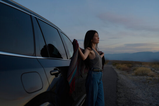 Young Woman Enjoys Serene Sunset by Her Car in the Mountains