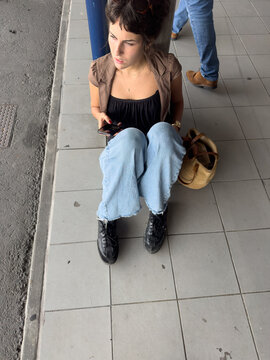 young woman waiting sitting on the ground waiting for bus