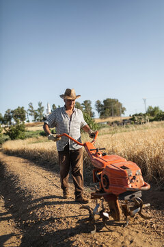 senior man tilling soil with electric cultivator