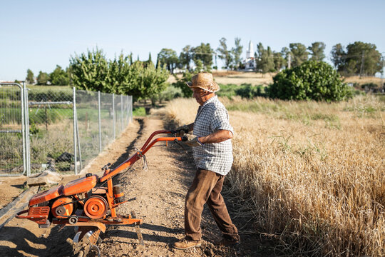 senior man tilling soil with electric cultivator