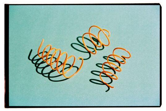 Bright orange spirals lie on a smooth green surface