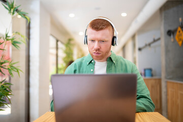 Focused office employee working on laptop with headphones