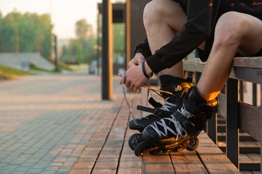 Young athlete tying shoelaces on inline skates sitting 