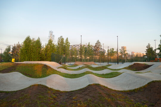 Pump track concrete waves winding through green park at sunset