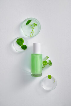 A cosmetic product surrounded by petri dishes and green leaves