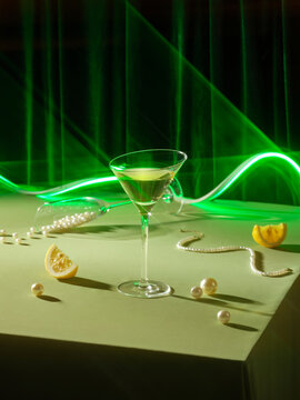 Stylish Green Cocktail with Pearls and Lemon Slice Under Neon Light