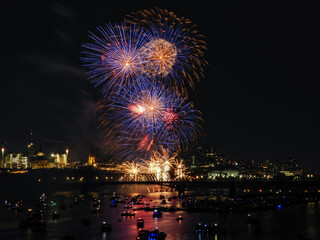 Fireworks in the night sky creating a bright display over the river filled with boating spectators