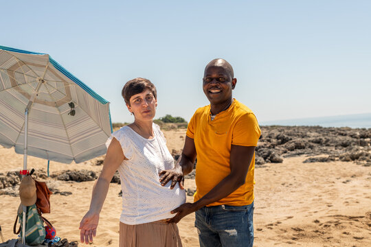 Happy couple expecting baby and having fun on the beach