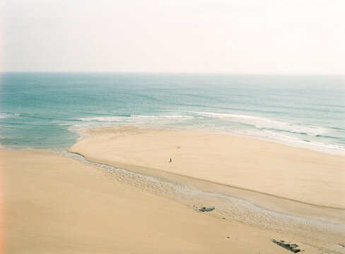 Far away unrecognizable person strolling on sandy beach
