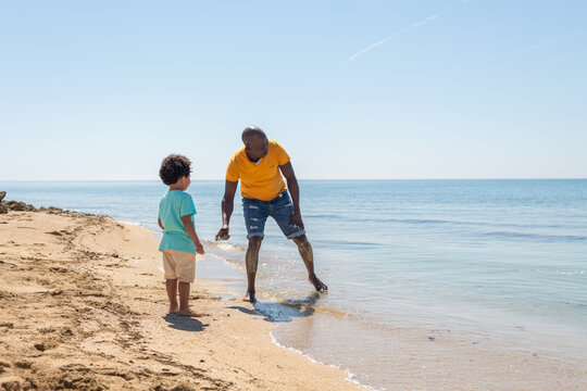 Father and son skipping stones by the water