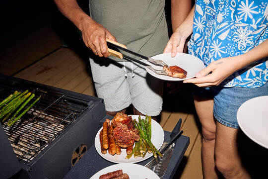 Man serves food from the grill to his friend