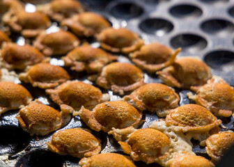 Dutch pancakes cooking on cast iron poffertjes pan also called poffertjes.