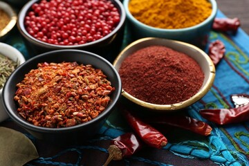 Different aromatic spices on blue tablecloth, closeup